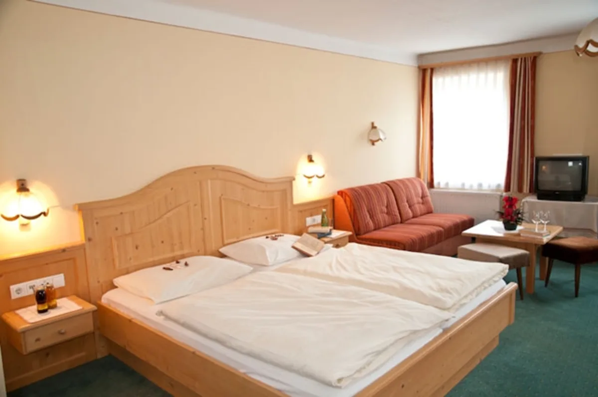 Doppelzimmer mit hellem Holzbett und Sitzecke